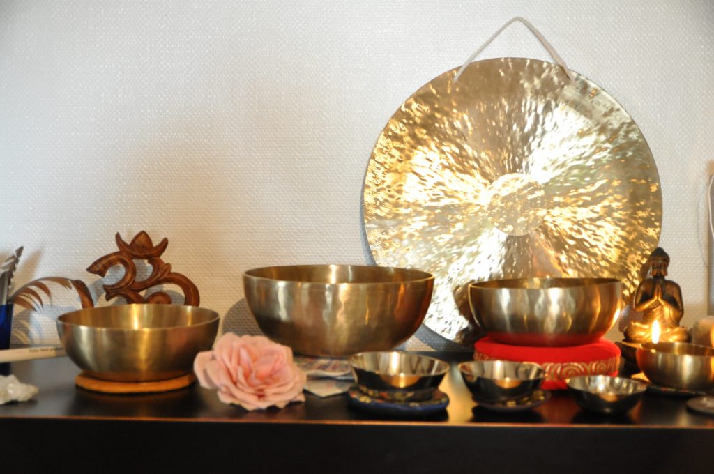 Hier siehst du eine Reihe von Klangschalen und Gong auf einer Kommode
